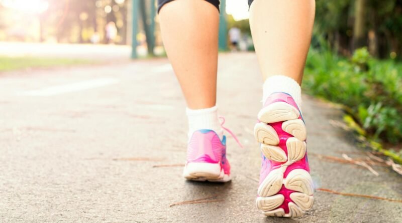 photo of woman wearing pink sports shoes walking