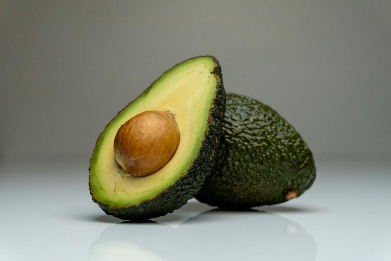close up one whole and one cut in half avocado