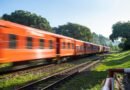 orange train speeds through lush countryside
