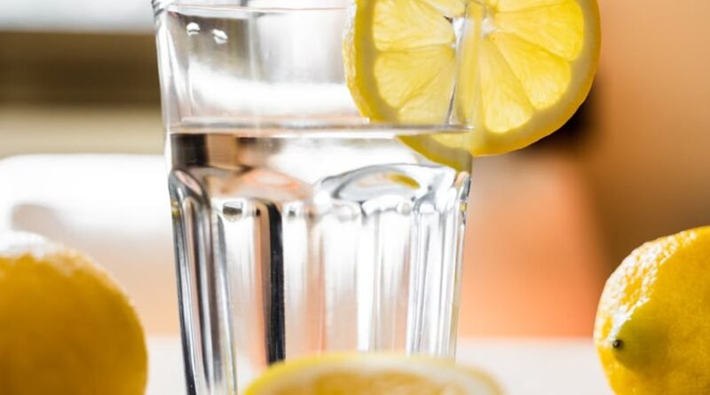 glass of cold water with lemon placed on table