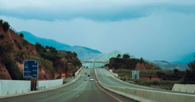 gray concrete road between brown and green mountains under blue sky