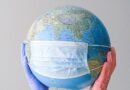 hands with latex gloves holding a globe with a face mask